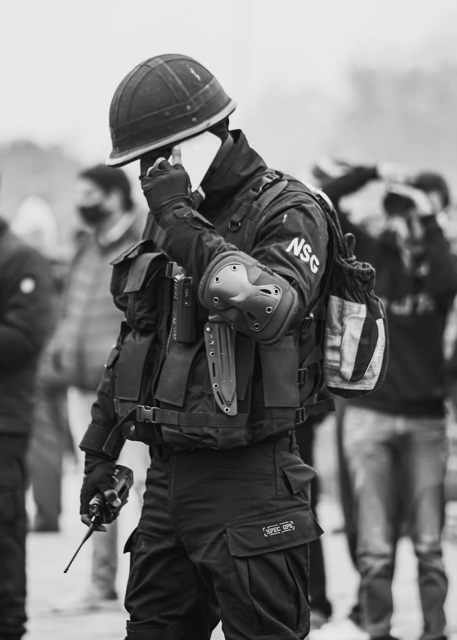 grayscale photography of a man in full safety gear having a phone call