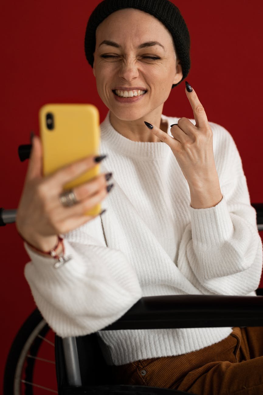excited woman in wheelchair smiling while having video conversation