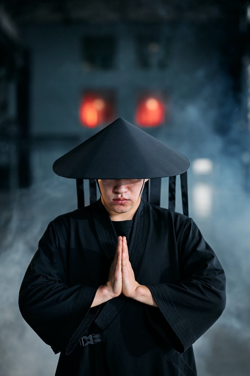 a man wearing black outfit and conical hat