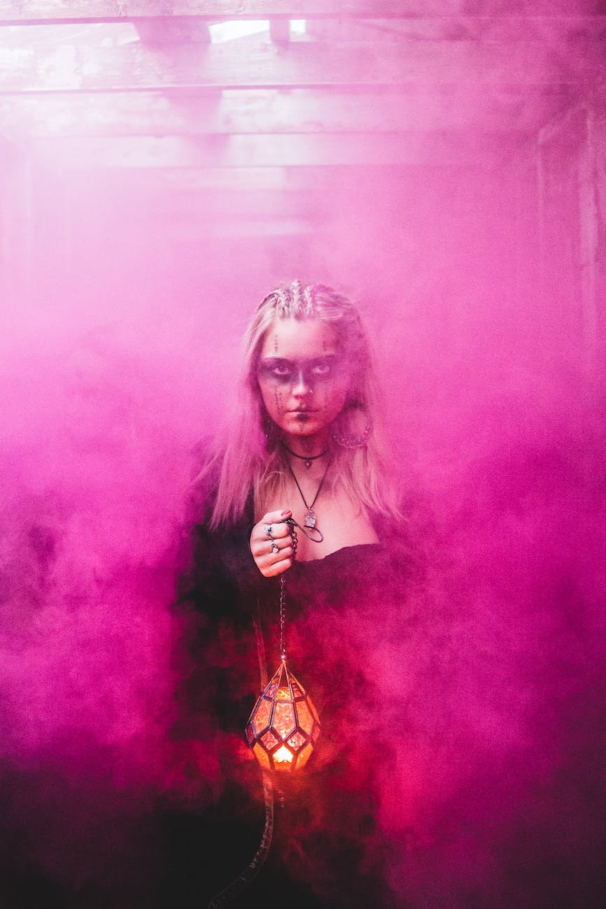 spooky witch with lamp in pink smoke