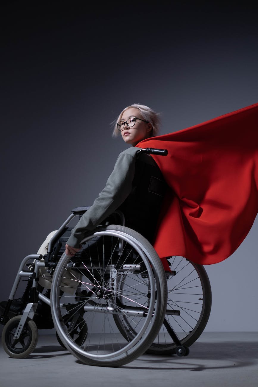 teenage girl sitting on wheelchair with a cape